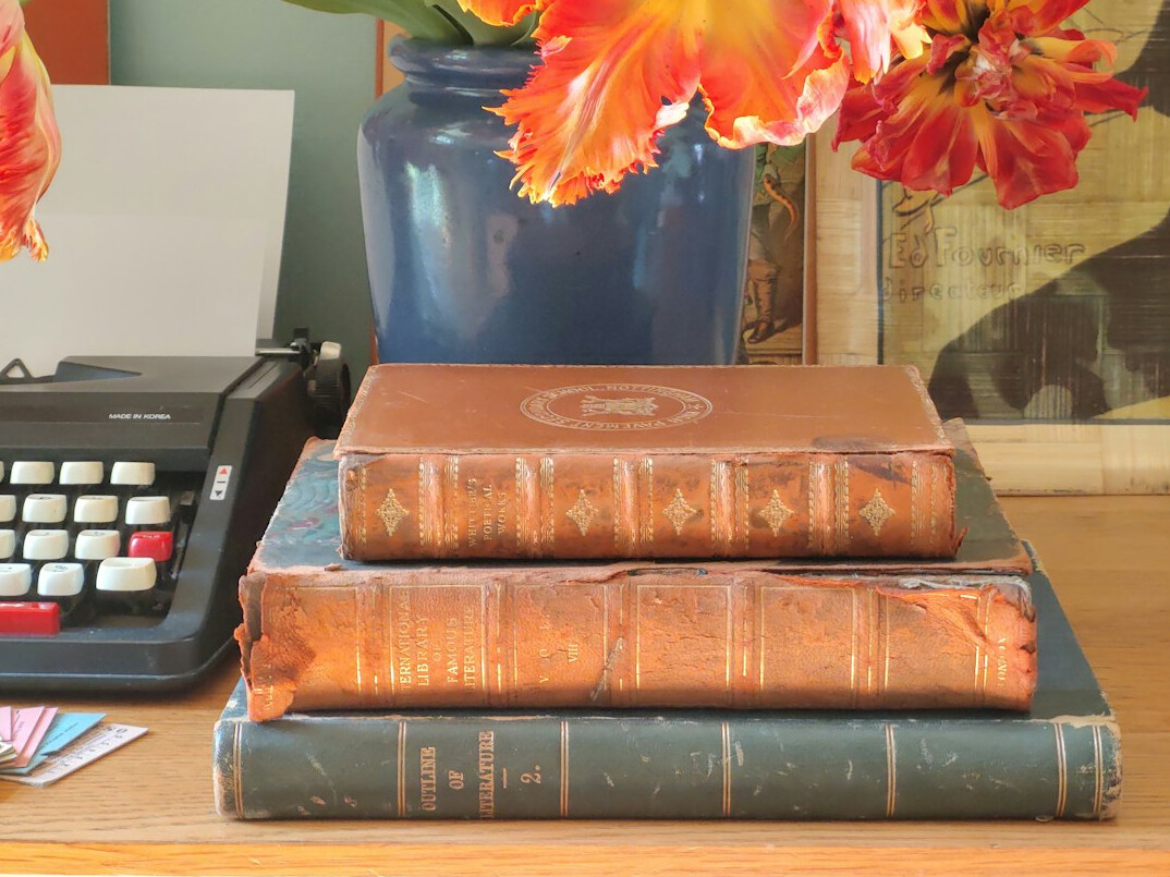 Stack of old leather-bound books on a wooden shelf